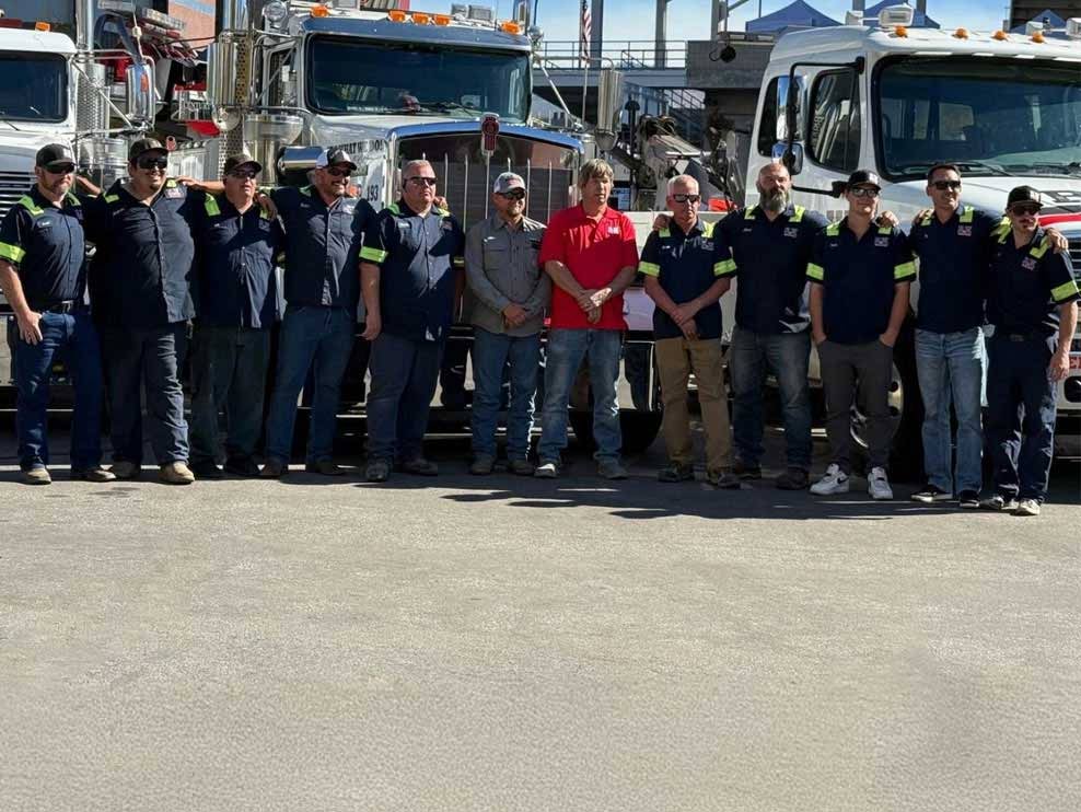 B&W Wrecker Service team of drivers standing together in front of heavy-duty tow trucks